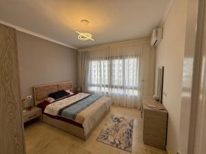 a bedroom with a bed and a large window at Celia -1 Bedroom Beauty in Madīnat al Amal