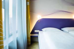 a bedroom with a bed with a purple headboard and a window at Prize by Radisson, Antwerp City in Antwerp