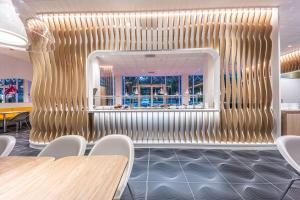 a restaurant with wooden tables and chairs and a gold wall at Prize by Radisson, Antwerp City in Antwerp