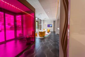a room with pink lights on the walls and a room with chairs at Prize by Radisson, Antwerp City in Antwerp