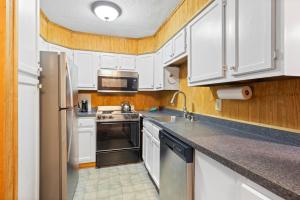 a kitchen with white cabinets and a sink and a refrigerator at Leatherbark 103A 3BR 2BA Quiet And Serene Private Deck WiFi in Snowshoe