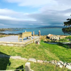 un banco de madera sentado en la parte superior de un campo junto al agua en The Sea House, en Dungloe