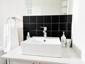 a white sink in a bathroom with a black tiled wall at Coastal Beach & Mountain Retreat in Cape Town +42 photos
