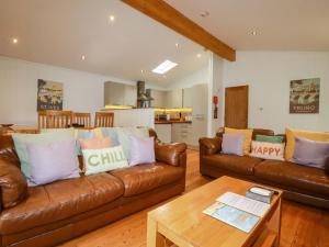 una sala de estar con 2 sofás de cuero marrón y una mesa. en 6 Streamside, en Looe
