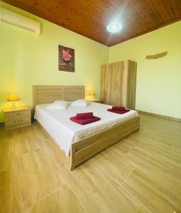 a bedroom with a large bed with red pillows on it at Fergani Apartments in Moúdhros