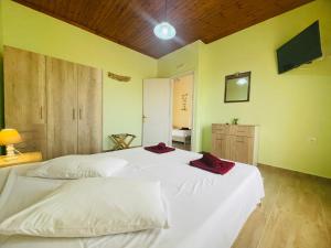 a bedroom with a large white bed with red napkins on it at Fergani Apartments in Moúdhros