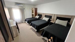 una camera d'albergo con due letti e una finestra di Hotel Plaza a Formosa Altre 11 foto