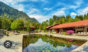a swimming pool in front of a building with mountains at Cabaña 8 a 9 personas ideal 2 matrimonios y niños in Coñaripe