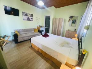 a bedroom with a large white bed and a couch at Fergani Apartments in Moúdhros