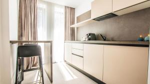 a kitchen with white cabinets and a stool in a room at Central Carol 1 in Bucharest
