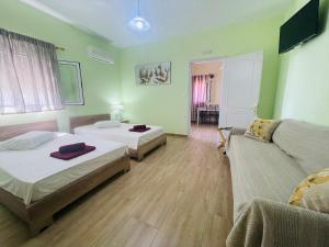 a hotel room with two beds and a couch at Fergani Apartments in Moúdhros