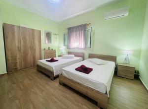 two beds in a room with green walls and wooden floors at Fergani Apartments in Moúdhros