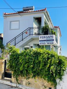 a white house with a sign for a fern castle at Fergani Apartments in Moúdhros