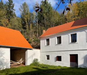 a white building with an orange roof and a garage at Neu renovierte Mühle, Einzellage im Waldviertel in Scheideldorf