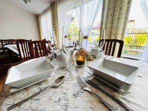 a dining room table with plates and utensils on it at Dom Wypoczynkowy Bajka in Krynica Zdrój