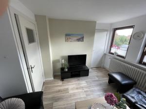 Una sala de estar con un televisor de pantalla plana y un sofá. en Ferienwohnung Alice, en Burhave