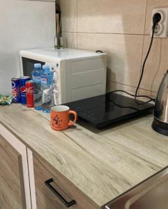 una tazza di caffè seduta su un bancone accanto a un forno a microonde di Apartman 11 a Leskovac