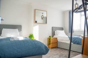 ミルトン・キーンズにある3 Bedroom home in Milton Keynes with Free Parking, WiFi and SKY TVのベッド2台と鏡のある寝室