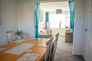ミルトン・キーンズにある3 Bedroom home in Milton Keynes with Free Parking, WiFi and SKY TVのダイニングルーム(テーブル、青いカーテン付)