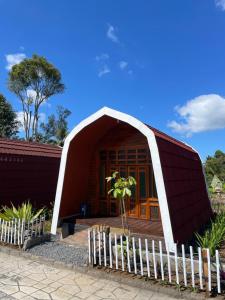 a small house with a red roof and a fence at Indah Damai Cottages in Sidomukti