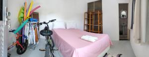 - une chambre avec un lit avec une couverture rose et un vélo dans l'établissement Casa do Mar, à Salvador