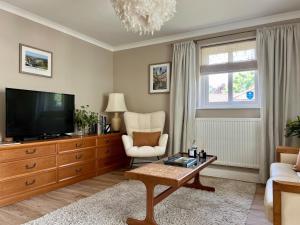 a living room with a television and a chair at Leaze Garden Cottage - Frome in Frome