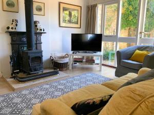 a living room with a fireplace and a flat screen tv at The View Cottage - Tennis Court - Nr Frome, Longleat in Frome