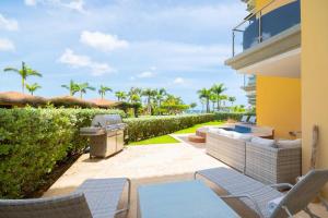 a patio with chairs and a grill and palm trees at Beachfront - Garden Delight 2BR condo - E125-2 in Palm-Eagle Beach