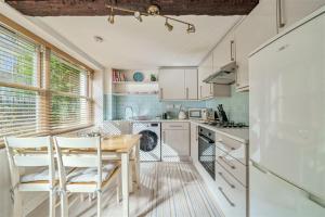 a kitchen with a wooden table and white cabinets at Apple Cottage - Central Frome - Outdoor Space in Frome