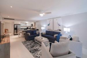 a living room with blue couches and a kitchen at Beachfront - Garden Delight 3BR condo - E125 in Palm-Eagle Beach