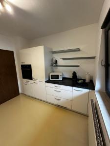 a kitchen with white cabinets and a microwave at VDM Ferienwohung Pfungstadt in Pfungstadt