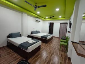 two beds in a room with a green ceiling at Kalapani Nest in Port Blair +11 photos
