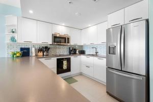 a kitchen with white cabinets and a stainless steel refrigerator at Beachfront - Emerald View 2BR condo - P416 in Palm-Eagle Beach