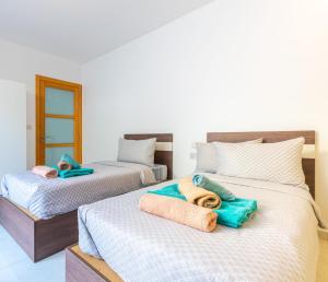 two beds with towels on them in a room at New Spacious Apartment 3 Bdr 2 Bth Bugibba 124 with View in St. Paul's Bay