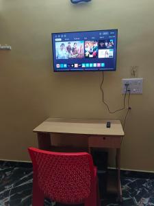 a desk with a television on a wall with a red chair at La Baie Homestay in Puducherry