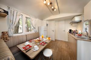 a living room with a table and a kitchen at Albatross Mobile Homes on Camping Cisano & San Vito S. p. A. in Bardolino +5 photos