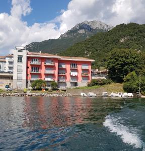a red building next to a body of water at Lake Como Casa la Rosa wonderful view in Abbadia Lariana