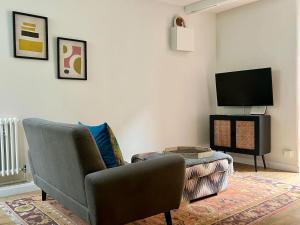 ein Wohnzimmer mit einem Stuhl und einem Flachbild-TV in der Unterkunft Cosy Weavers Cottage - Heart of Frome in Frome