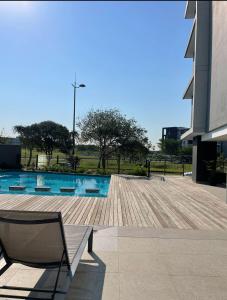 Umhlanga Millenial Deluxe في ديربان: مسبح مع كرسي بجانب مبنى
