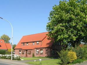 una casa de ladrillo con techo naranja junto a un árbol en Ferienwohnung Alice, en Burhave