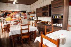 a restaurant with tables and chairs and a kitchen at Hotel Modelo Rio Pardo in Ribas do Rio Pardo