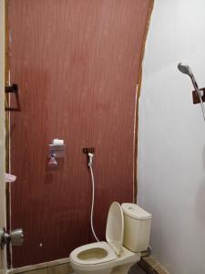 a bathroom with a toilet and a wooden door at Indah Damai Cottages in Sidomukti