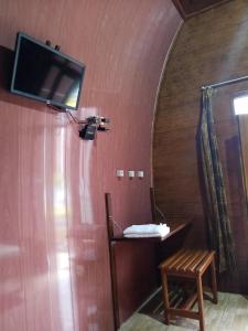 a room with a tv on the wall and a chair at Indah Damai Cottages in Sidomukti