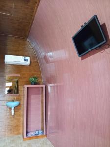a bathroom with a flat screen tv on a wall at Indah Damai Cottages in Sidomukti