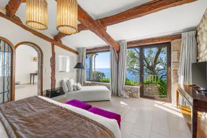 a bedroom with a king sized bed and large windows at La Chèvre d'Or in Éze