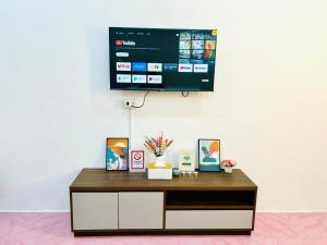a tv hanging on a white wall with a table at Mali house Hatyai in Hat Yai