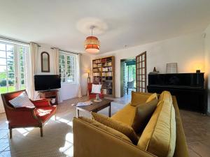 a living room with a couch and a tv at La Maison du Tilleul avec Piscine couverte chauffée in Saint-Sulpice-sur-Risle