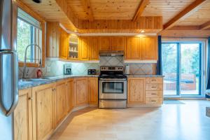 una cucina con mobili in legno e una stufa di Au Chic Chalet des Chutes Chic Cottage a Sainte-Melanie
