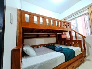 una litera de madera con dos toallas azules encima en Cozy 2BR with Balcony in Mines View Park by Peniel's Getaway, en Baguio 21 fotos más