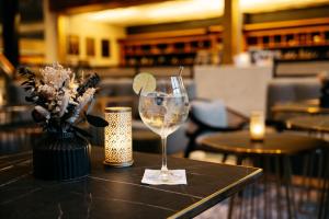 a table with a wine glass and a vase with a lime at MONDI Hotel Bellevue Gastein in Bad Gastein +37 photos